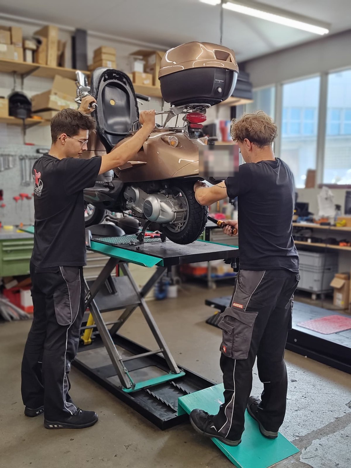 Zwei Mechaniker arbeiten gemeinsam an einem Roller auf der Hebebühne in St. Gallen
