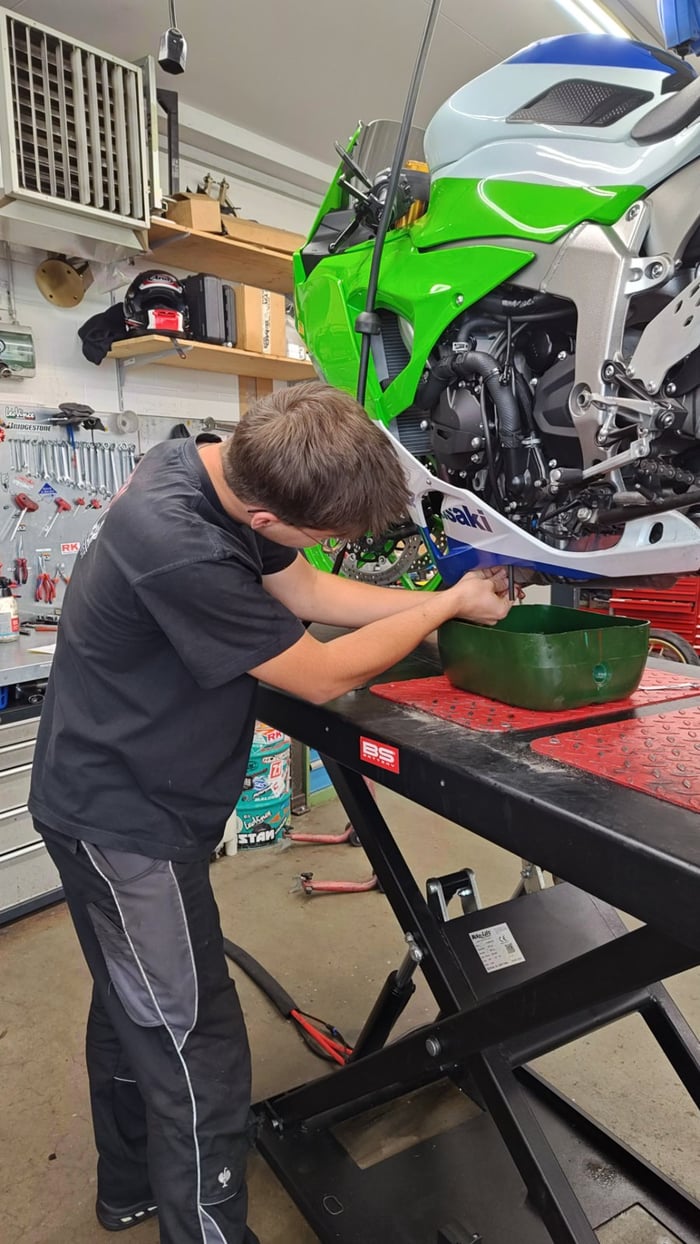 Mechaniker beim Ölwechsel an einer grünen Kawasaki Ninja in der Werkstatt St. Gallen
