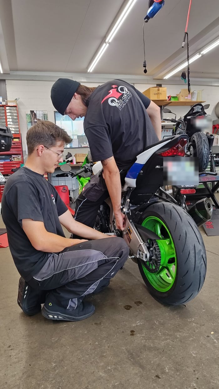 Zwei Mechaniker prüfen Kette und Ritzel an einer Kawasaki in der Werkstatt von Moto-Center WEST